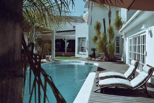 温特和克Belvedere Boutiqe Hotel的一座房子旁带两把椅子的游泳池