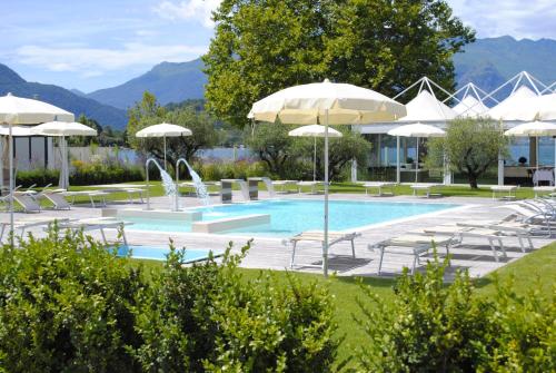 科利科Seven Park Hotel Lake Como - Adults Only的一个带遮阳伞和椅子的游泳池以及一个游泳池