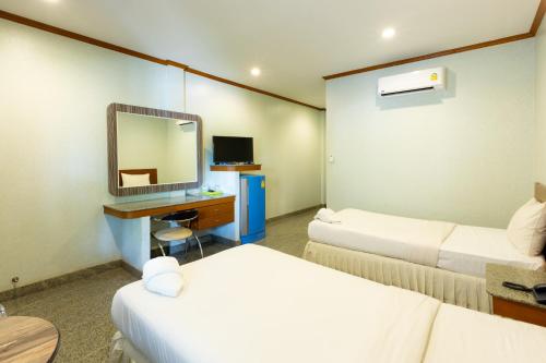 Sangkhaโรงแรมมณีสังขะ的酒店客房配有两张床和一张带镜子的书桌