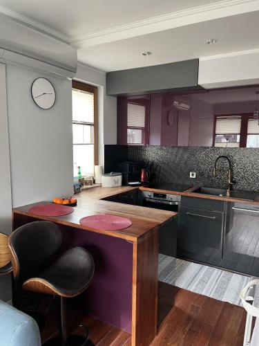 索波特Urus Home Sopot的厨房配有紫色橱柜和木制台面