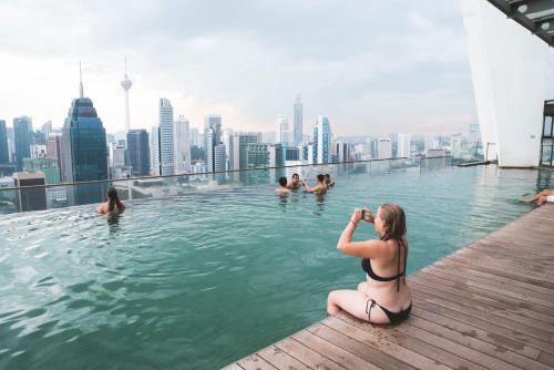 吉隆坡The Common Room @ Regalia的一位在无边游泳池里拍人照片的女人