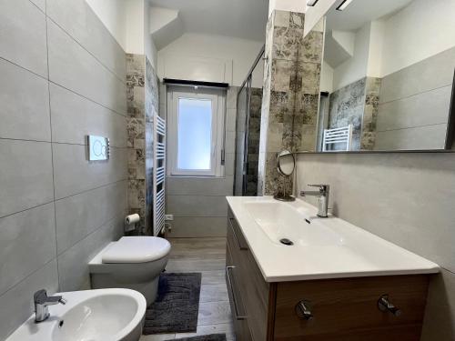 格拉多Condominio Martini的浴室设有2个水槽、卫生间和镜子。