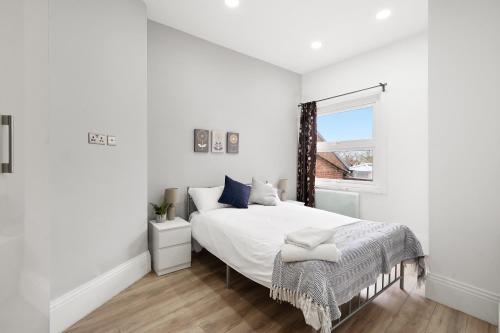哈罗3BR Duplex Penthouse Harrow centre的白色的卧室设有一张大床和一个窗户