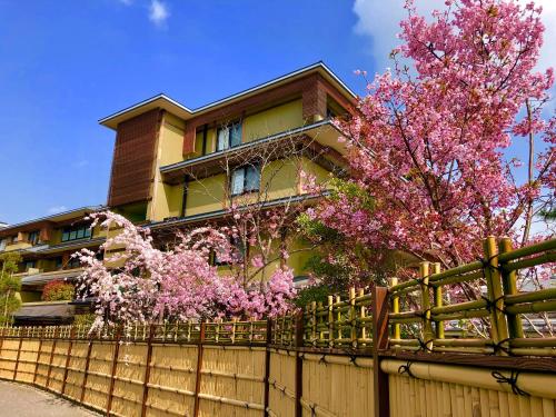 京都Kadensho, Arashiyama Onsen, Kyoto - Kyoritsu Resort的一座带围栏的房子和一棵带粉红色花卉的树