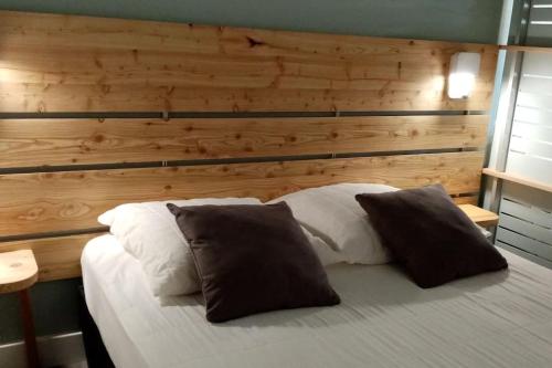 孔佩尔Gîte et chambre d'hôtes Chez Marie的一张带两个枕头的床和木墙