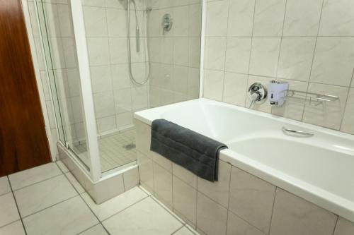 比勒陀利亚VillaZek a modern 2 bedroom open- plan apartment with parking的带淋浴和水槽及蓝毛巾的浴室