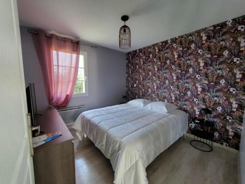 丰特奈勒孔特Hortensia, Gîte famille et amis的一间卧室设有一张床和花卉墙