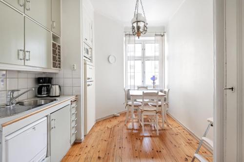赫尔辛基WeHost Spacious Studio for 5 with a Kitchen的厨房配有白色橱柜和桌椅