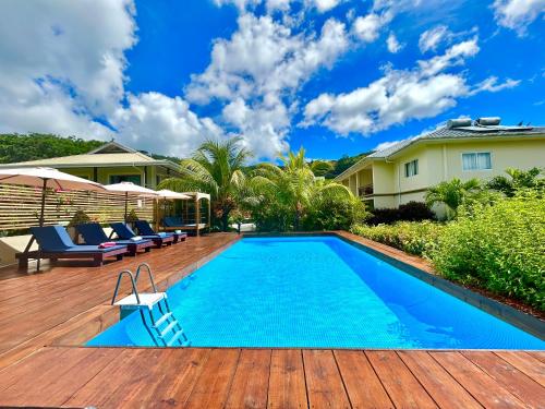 马埃岛The Seaboards Apartments Seychelles的一个带椅子的甲板上的游泳池以及一座房子