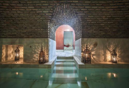 托莱多RIAD MEDINA MUDEJAR BAÑOS ARABES的一间设有游泳池和砖墙的房间