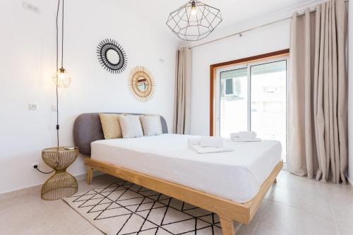 波尔蒂芒Solemar - 2Pools - WIFI 500MBps - AC - Portimão的白色的卧室设有一张大床和一个窗户