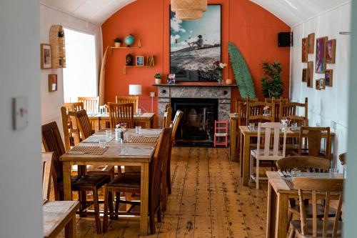 Slievemore纯魔法旅舍的餐厅设有木桌、椅子和壁炉