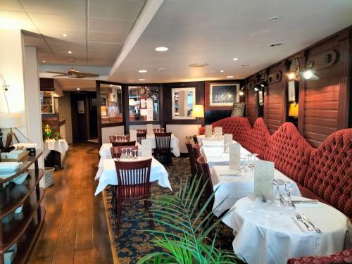 瑟堡Logis HOTEL RESTAURANT La Régence的一间设有白色桌子和红色椅子的餐厅