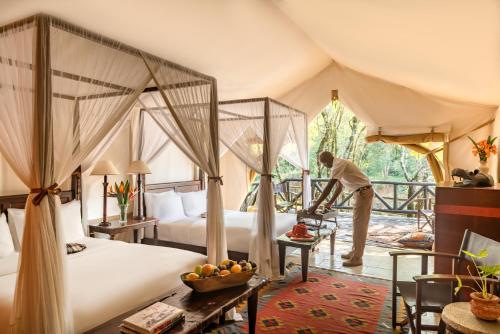 Aitong费尔蒙马拉野生动物俱乐部酒店的帐篷卧室内的一名男士配有两张床