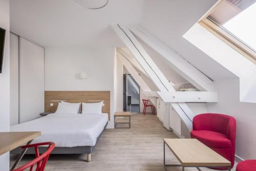 格勒诺布尔家乐中心公寓式酒店的一间卧室配有一张床和一张红色椅子