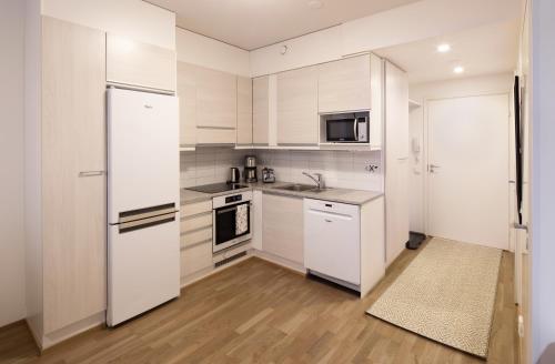 罗瓦涅米First Aparthotel Dasher的厨房配有白色橱柜和白色冰箱。