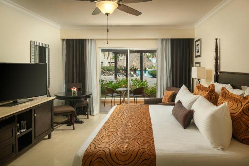 蓬塔卡纳Jewel Palm Beach的一间卧室设有一张大床和一台平面电视。
