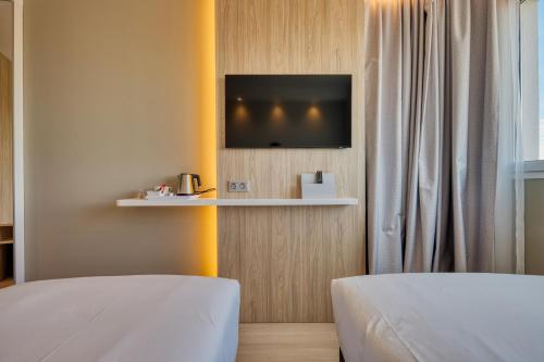 马德里Holiday Inn Express - Madrid - Airport, an IHG Hotel的客房设有两张床和一台墙上的电视