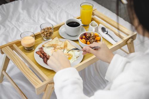 齐克拉约Hotel Santa Rosa的床上的早餐盘,包括一盘食物