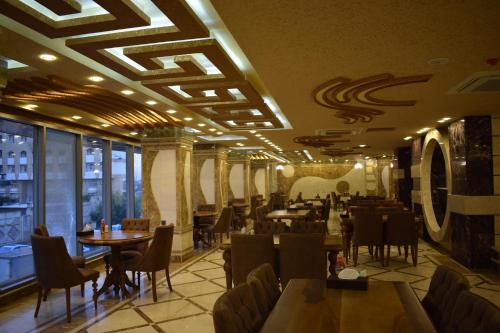 纳杰夫Royal Eagle Hotel的一间在房间内配有桌椅的餐厅