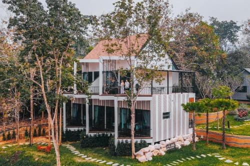 拉博康村VeeVaree Riverkwai Resort的带阳台和树木的大型白色房屋