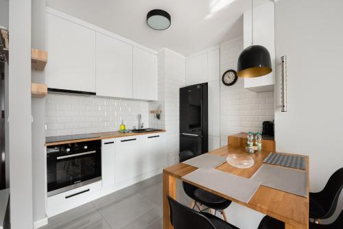 华沙Metro Płocka Exclusive Apartment的厨房配有白色橱柜和木桌