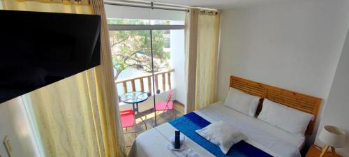 帕拉卡斯Paracas Guest House的一间卧室设有一张床,阳台配有电视。