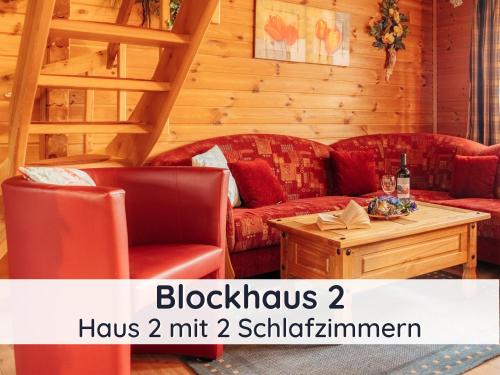 巴特萨克萨Der Fuchsbau - 3 separate Blockhäuser - ruhige Lage - 50m bis zum Wald - eingezäunter Garten的客厅配有两张红色的沙发和一张桌子