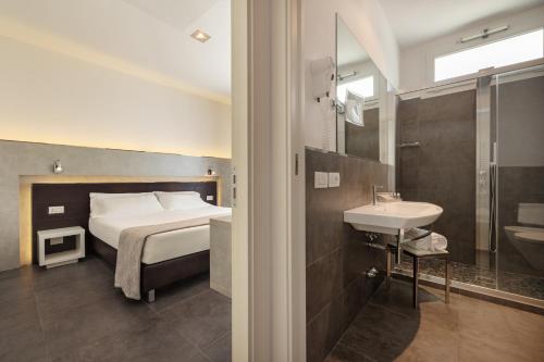 里米尼巴尔迪尼尼酒店的一间卧室配有一张床,浴室设有水槽