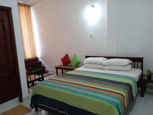 康提亚历克斯家庭旅馆的一间卧室配有一张带彩色条纹毯子的床