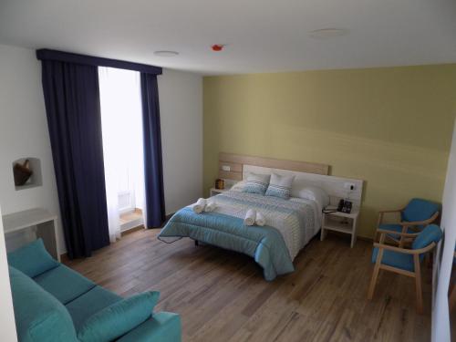 马德里德霍斯Hotel Rural SUEÑOS DEL QUIJOTE的一间卧室配有一张床和一张蓝色的沙发