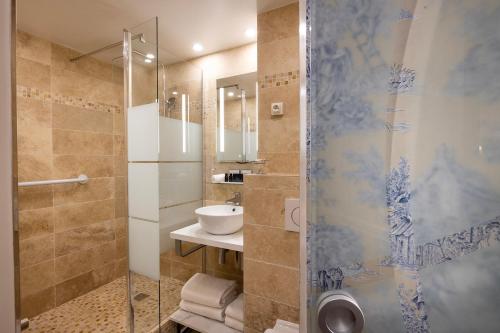 巴黎驿站酒店的一间带玻璃淋浴和水槽的浴室