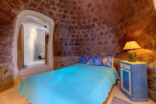Éxo GoniáCharming Restored 300yr-0ld Guest House的一间卧室,在石墙内配有一张蓝色的床