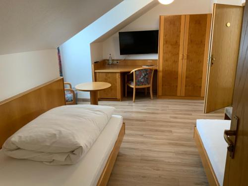 HohenstadtGasthaus Sonne的一间卧室配有一张床和一张书桌及电视