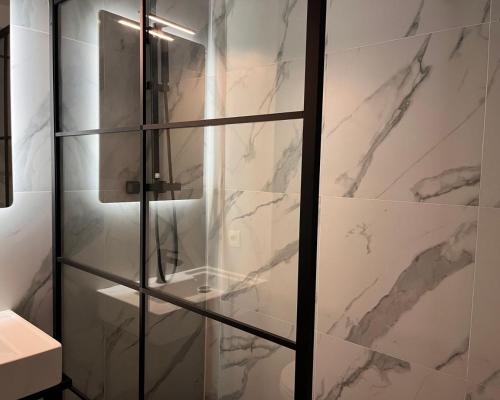 布鲁塞尔Hôtel La Pièce的浴室设有玻璃淋浴间和大理石墙壁。