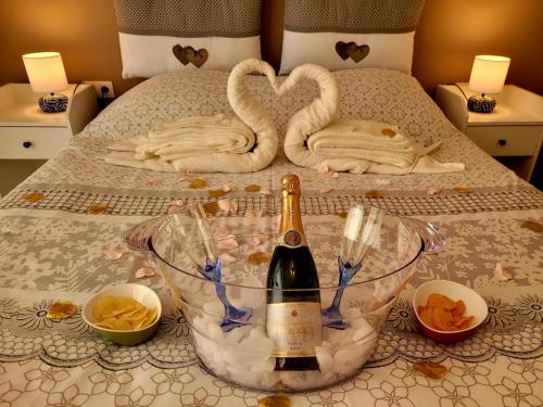 Sainte-OdeLes chambres de la fontaine de brul的一张带一瓶香槟和天鹅毛巾的床