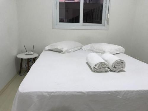 南卡希亚斯Pasqualetto的一张带两个枕头的白色床和窗户