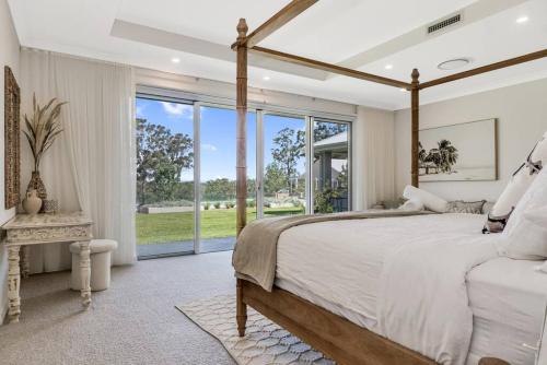 LochinvarLuxury Hunter Valley Estate的一间卧室设有一张大床和一个大窗户