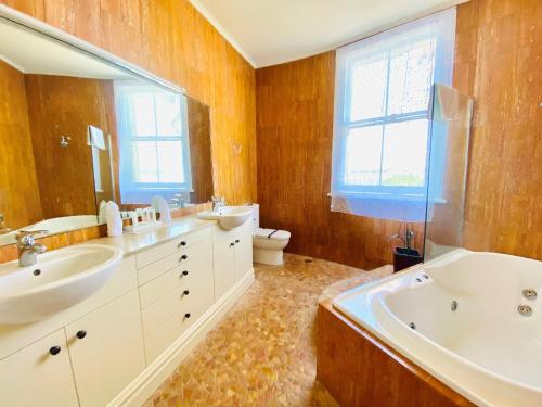 奥克兰艾斯普奈酒店的一间带两个盥洗盆、浴缸和卫生间的浴室
