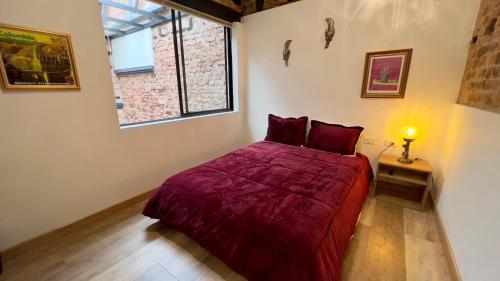 波哥大Las Aguas Inn的一间卧室配有一张带红色床罩的床和窗户