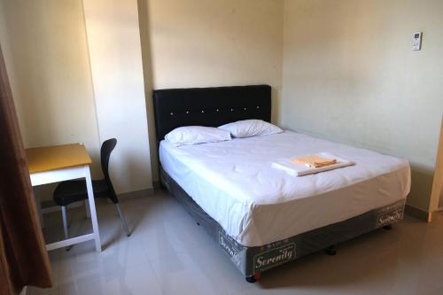 NgabeanDANGAU DATUK GUESTHOUSE的一张位于小房间的床,配有一张桌子和一张四柱床