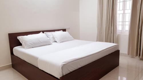 钦奈Chippy Apartments No.544的卧室内的一张带白色床单和枕头的床