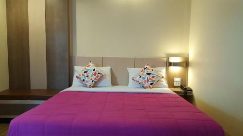 坤敬Kaen Nakorn Hotel的一间卧室配有一张带两个枕头的紫色床