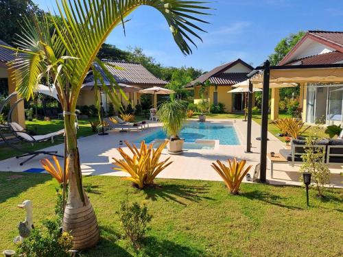 Ban ChamrungPool Villa, Resort, Mae Ramphueng Beach, Ban Phe, Rayong, Residence M Thailand的游泳池旁的棕榈树