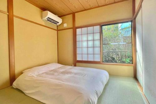 Ajiro雅 南熱海 温泉別荘 Ocean View Hotspring Villa的一间小卧室,配有床和窗户