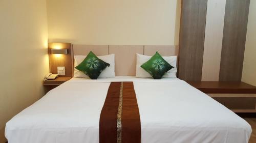 坤敬Kaen Nakorn Hotel的卧室配有带绿色枕头的大型白色床