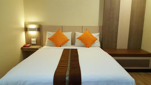 坤敬Kaen Nakorn Hotel的一间卧室配有一张带橙色枕头的大床