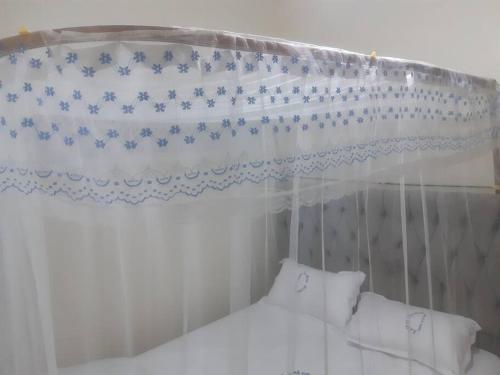 内罗毕LaMeg Homestay的白色天蓬床,带蓝色和白色窗帘
