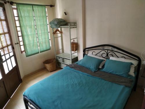 胡志明市Entire small house mins to everywhere!的一间卧室配有一张带蓝色床单的床和两个窗户。