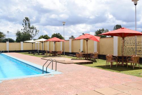 内罗毕LaMeg Homestay的一个带桌椅和遮阳伞的游泳池以及一个游泳池